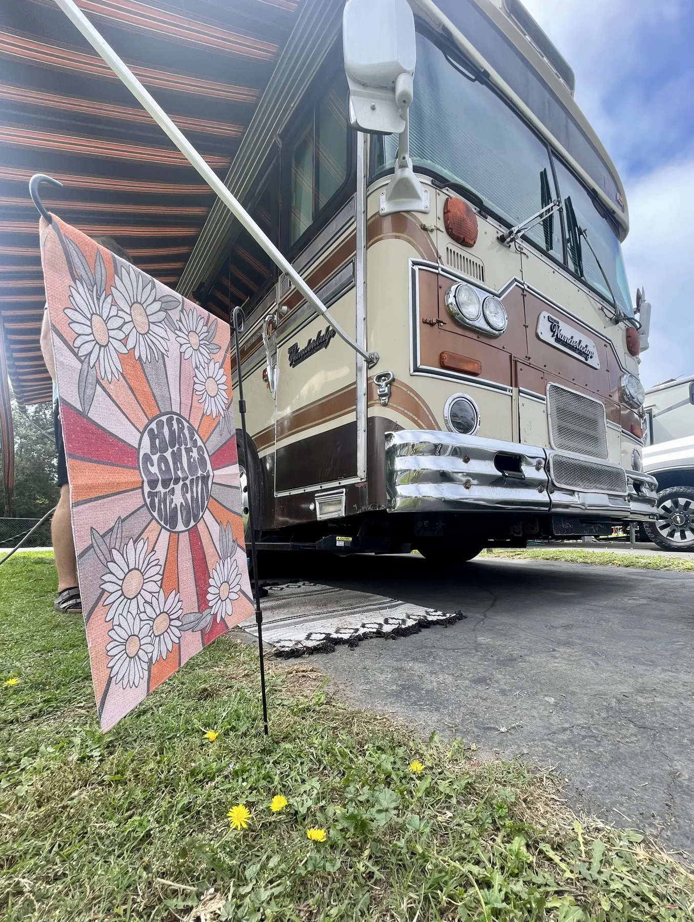 A low view of Woodstock’s cream and rust front, parked beside a colorful sign