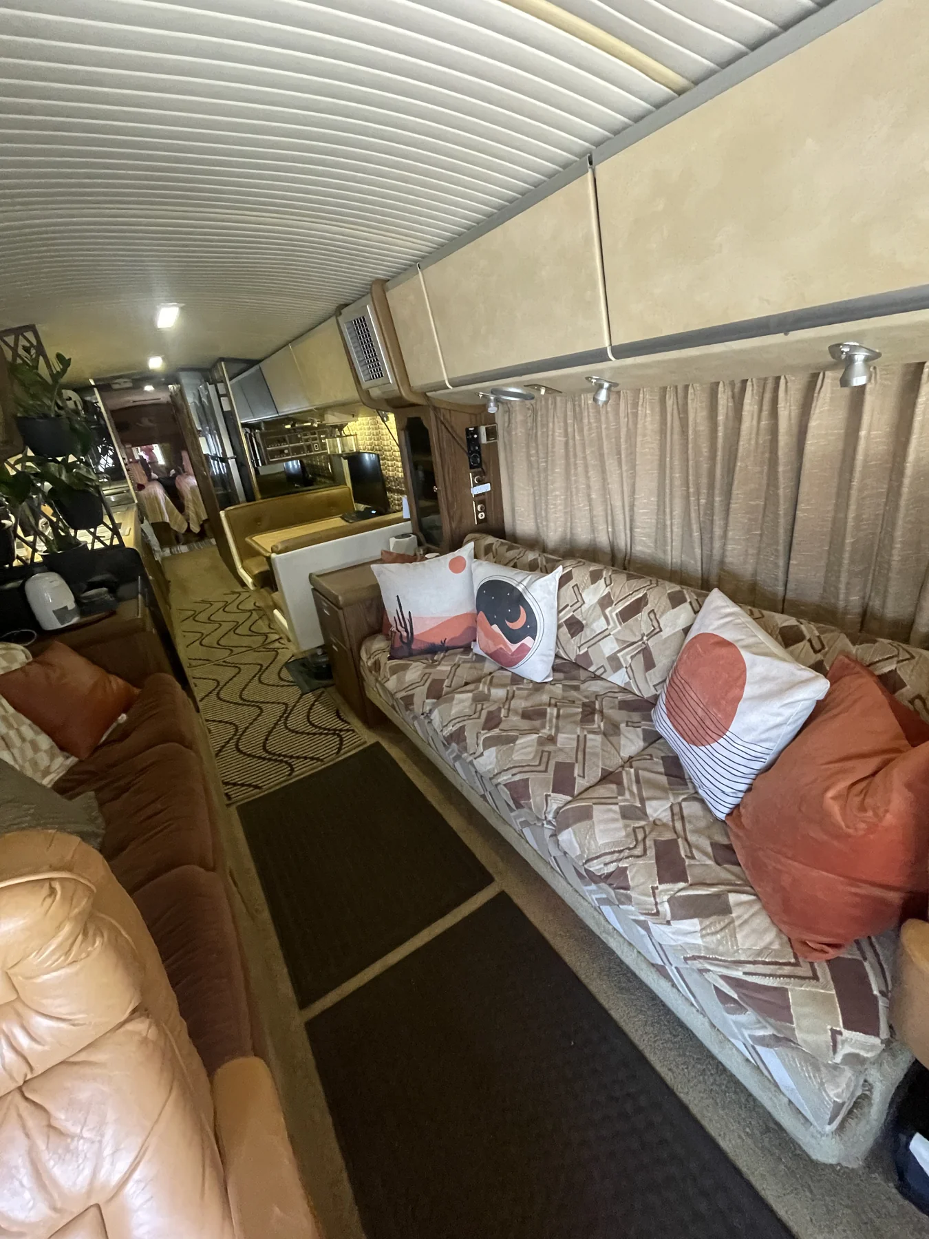 Inside Woodstock: a cozy couch with colorful pillows, curtains and warm wood details